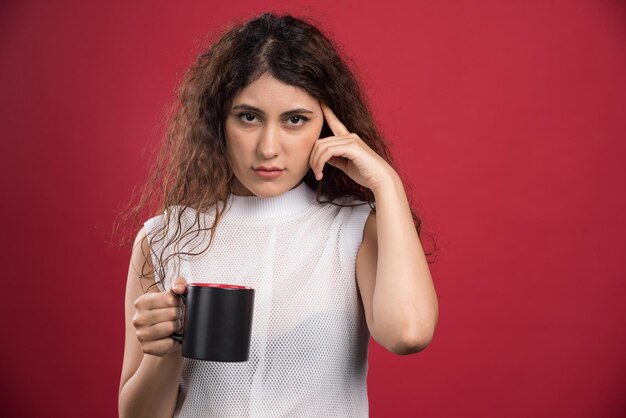 Mulher segurando xícara quente escura no vermelho