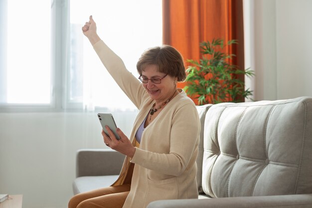 Mulher sênior com tiro médio segurando o telefone