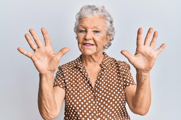 Mulher sênior de cabelos grisalhos vestindo roupas casuais mostrando e apontando para cima com os dedos número nove enquanto sorria confiante e feliz