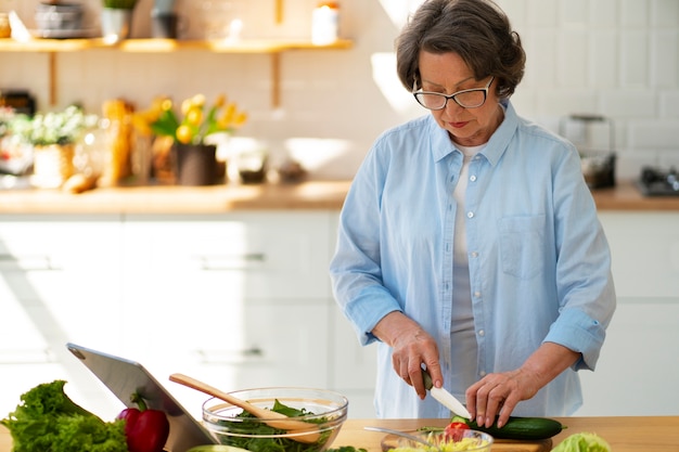 Foto grátis mulher sênior de tiro médio cozinhando na cozinha