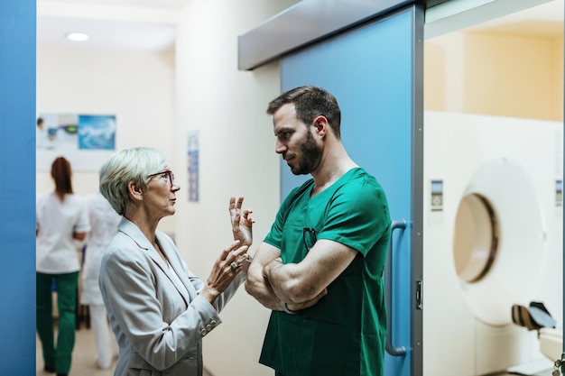 Mulher sênior e cirurgião se comunicando em pé no saguão do hospital
