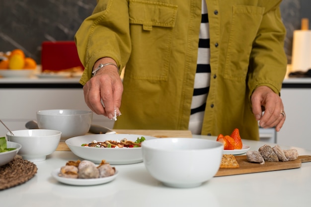 Mulher sênior fazendo prato com figos na cozinha