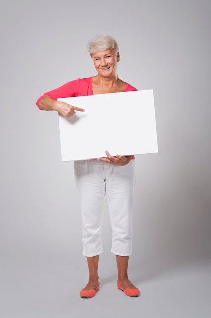 Mulher sênior feliz apontando para o quadro branco