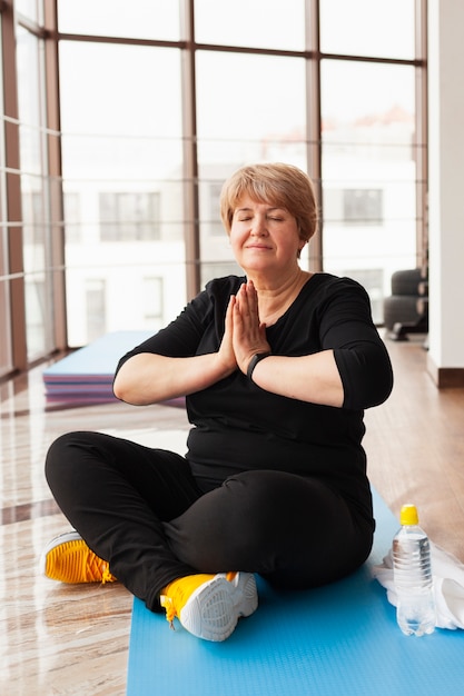 Foto grátis mulher sênior na academia fazendo yoga