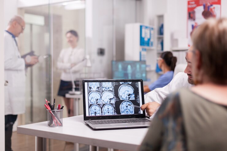 Foto grátis mulher sênior no consultório do hospital, olhando para a tomografia computadorizada do cérebro, enquanto discute com o médico sobre o diagnóstico. mulher jovem doente e médico idoso com cabelos grisalhos no corredor da clínica.