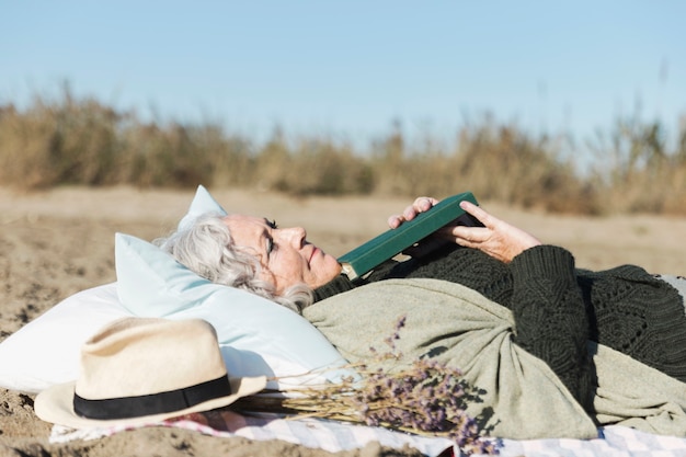 Mulher sênior pacífica que guarda o livro