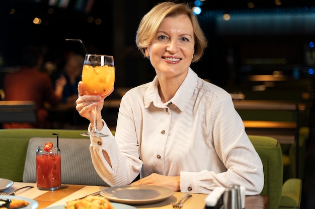 Mulher sênior posando com seu coquetel em um restaurante