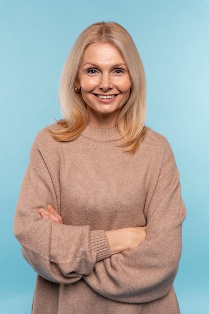 Mulher sênior posando e sorrindo contra um fundo azul