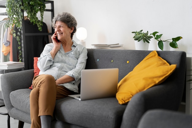 Mulher sênior sorridente de tiro completo sentada no sofá