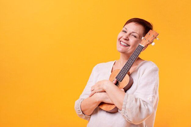 Mulher senior sorridente segurando ukulele