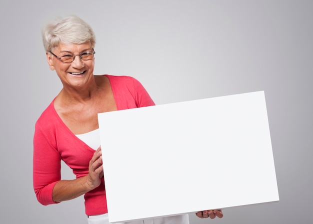 Mulher sênior sorridente segurando um quadro branco