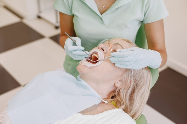 Mulher sênior, tendo tratamento dentário no consultório do dentista. Mulher está sendo tratada para dentes