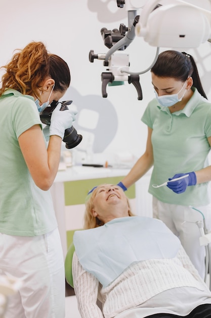 Mulher sênior, tendo tratamento dentário no consultório do dentista. O médico tira uma foto dos dentes do paciente.