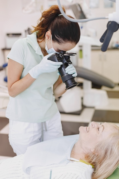 Mulher sênior, tendo tratamento dentário no consultório do dentista. O médico tira uma foto dos dentes do paciente.