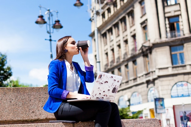 Foto grátis mulher senta na rua e trabalha com um laptop