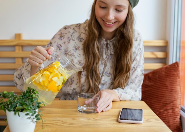 Mulher sentada à mesa, a meio tiro, a servir limonada