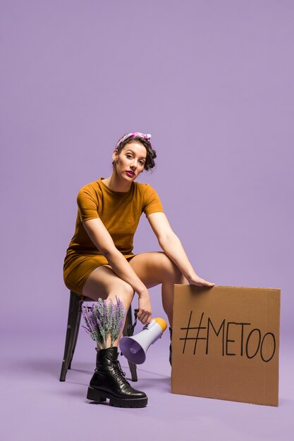 Mulher sentada e segurando papelão "eu também"