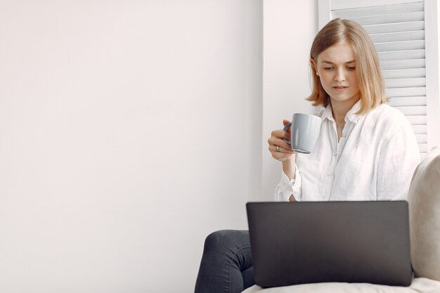 Mulher sentada em casa e usando um laptop