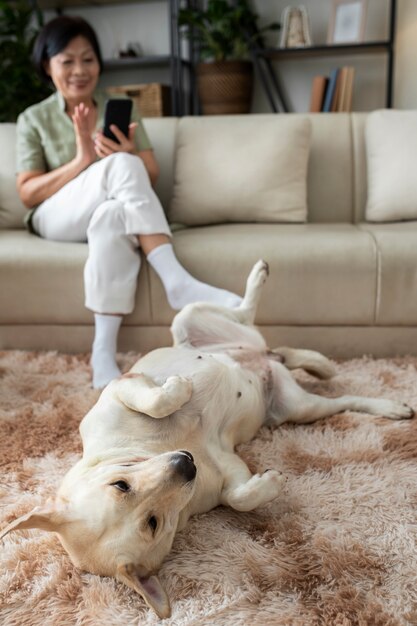 Mulher sentada em casa no sofá usando smartphone ao lado de seu cachorro