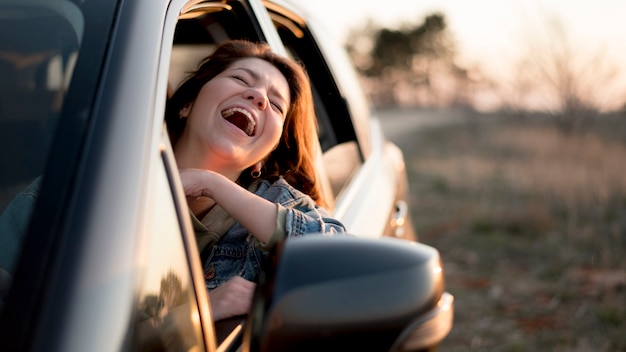 Mulher sentada em um carro e rindo