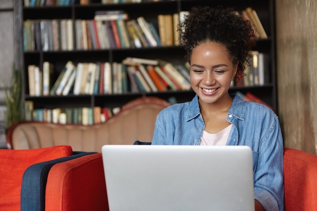 Foto grátis mulher sentada em uma biblioteca com seu laptop