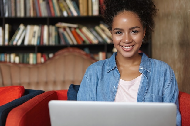 Mulher sentada em uma biblioteca com seu laptop