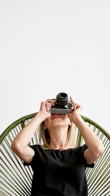 Foto grátis mulher sentada em uma cadeira e tirar uma foto