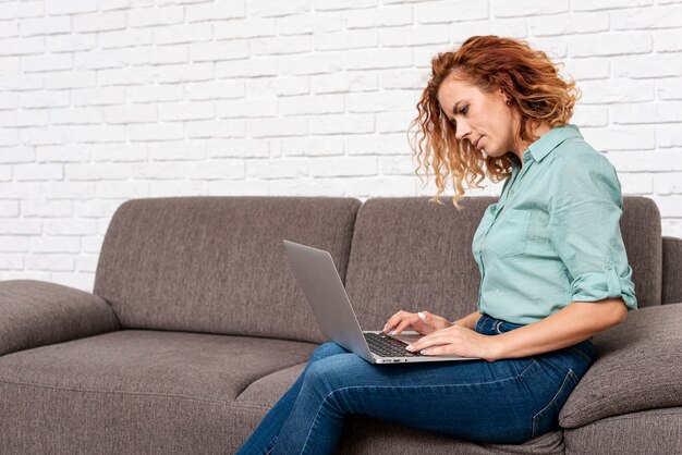 Foto grátis mulher sentada enquanto verifica o laptop