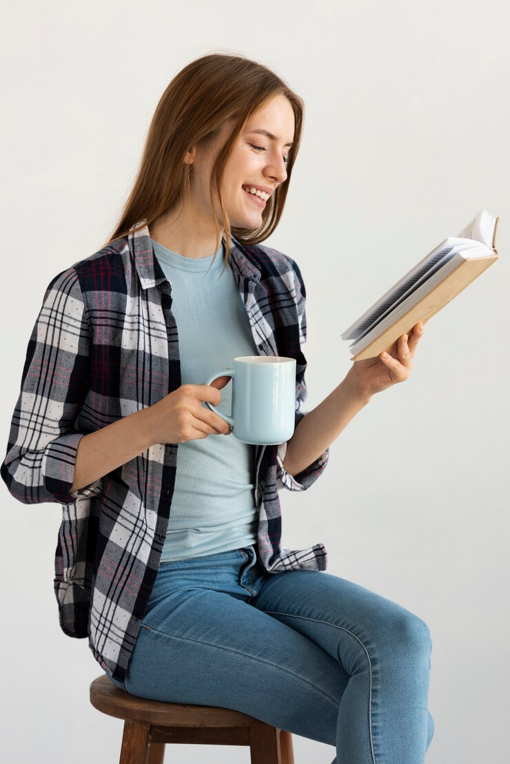 Foto grátis mulher sentada na cadeira enquanto lê um livro