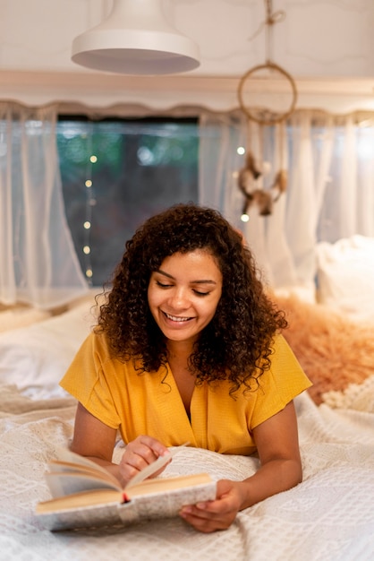 Foto grátis mulher sentada na cama a ler de frente