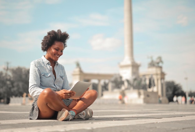 Foto grátis mulher sentada na rua usa um tablet