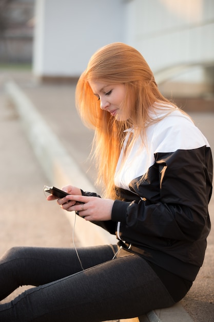 Mulher sentada no chão e olhando para o celular