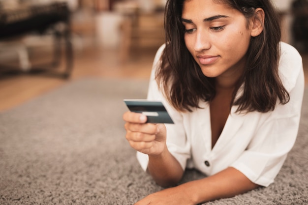 Foto grátis mulher sentada no chão e olhando para um cartão de crédito