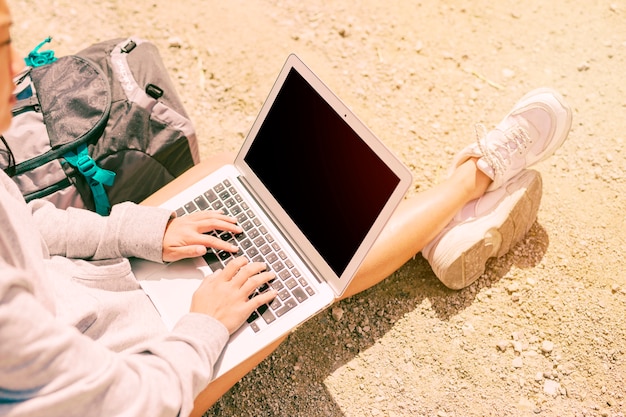 Mulher sentada no chão e trabalhando no laptop