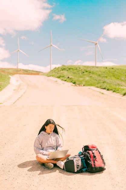 Foto grátis mulher sentada no meio da estrada e trabalhando no laptop