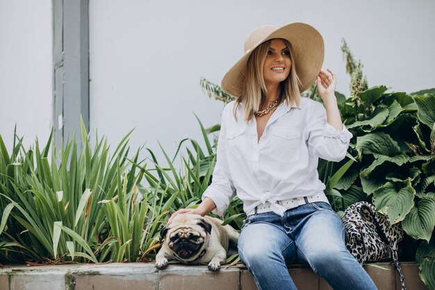 Mulher sentada no parque com seu cachorro pug