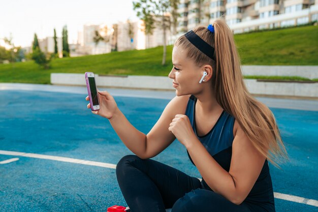 Mulher sentada no parquinho com um telefone nas mãos