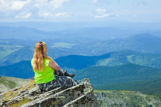 Mulher sentada no pico da montanha