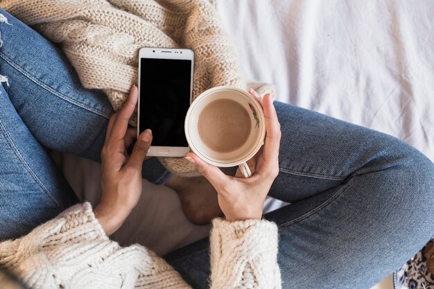 Mulher, sentando, cama, com, smartphone, e, café