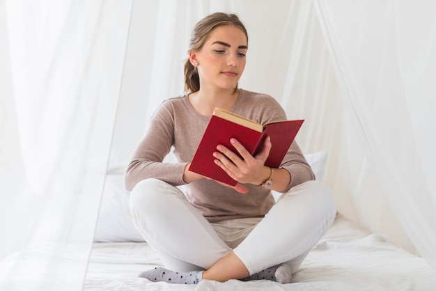 Mulher, sentando, cama, leitura, livro