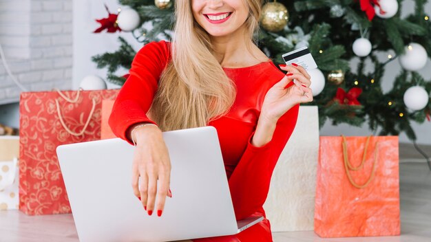 Mulher, sentando, com, laptop, e, cartão, perto, árvore natal