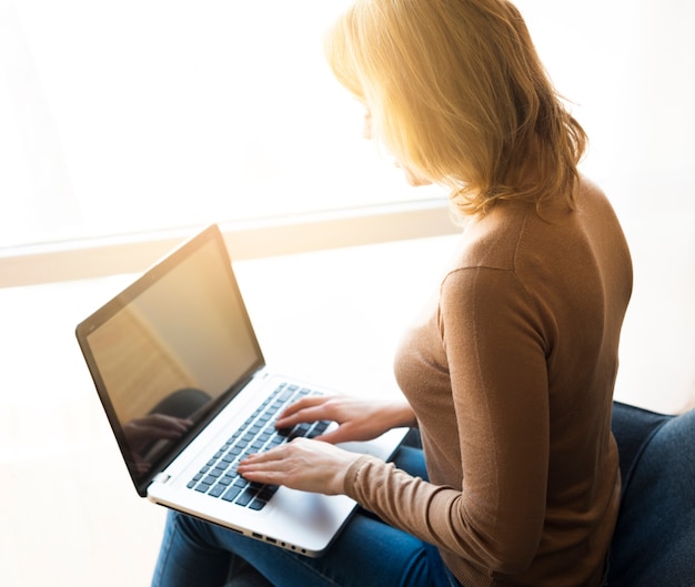 Mulher, sentando, e, usando computador portátil