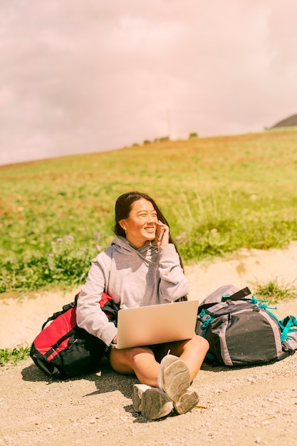 Foto grátis mulher, sentando, ligado, estrada, sorrindo, e, falando telefone móvel, entre, mochilas