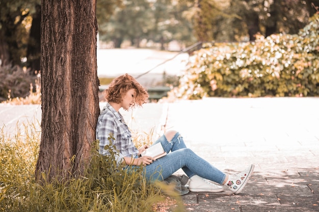 Foto grátis mulher, sentando, perto, árvore, e, livro leitura