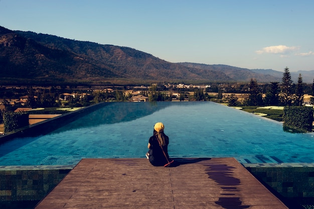 Mulher, sentando, por, poolside, com, vista montanha