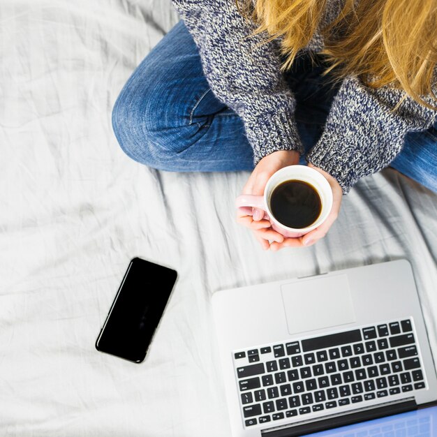 Mulher, sentar-se cama, com, laptop, e, café