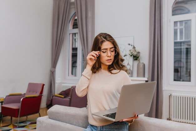 Mulher séria e inteligente de óculos posando com laptop