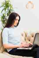 Foto grátis mulher séria sentada no sofá com laptop