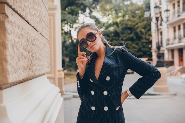 Mulher sexy elegante vestida com um terno de smoking elegante andando pela cidade no dia de primavera de verão