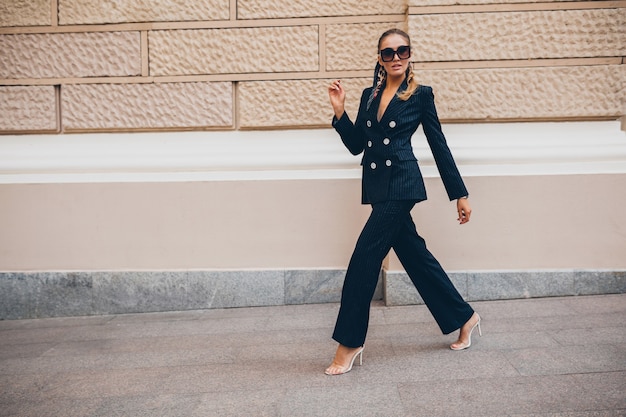 Mulher sexy elegante vestida com um terno de smoking elegante andando pela cidade no dia de primavera de verão